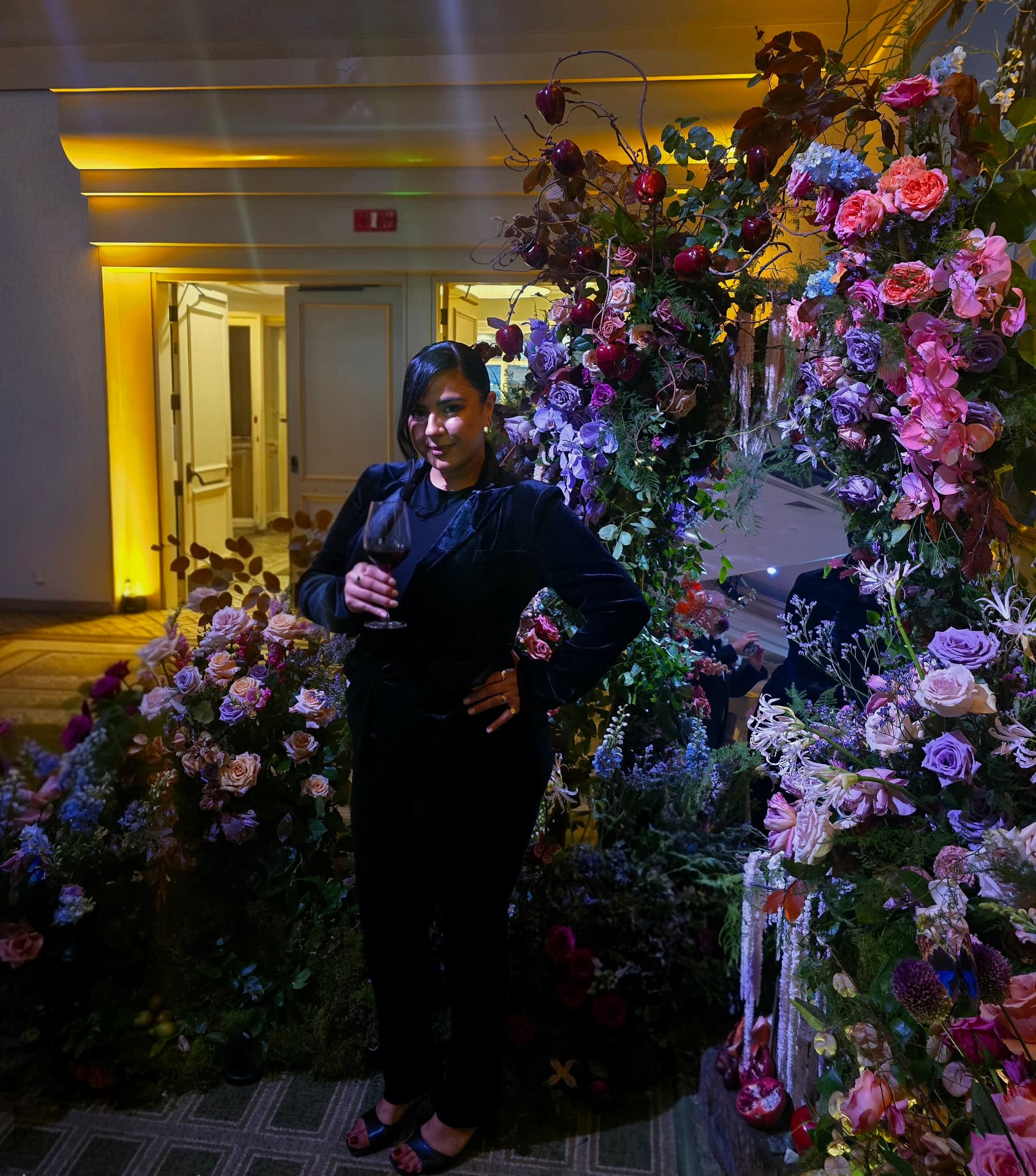 Atisha Lee, owner and lead designer of Allure Floral Designs, standing with an elaborate floral installation